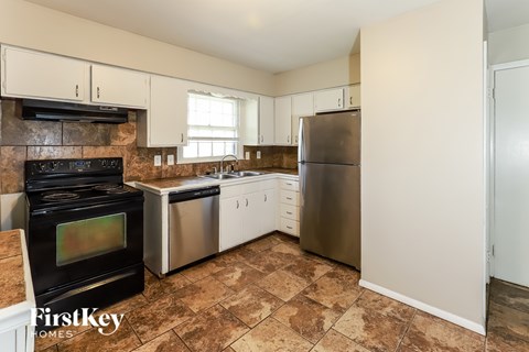 A kitchen with a black stove top oven and a stainless steel refrigerator.