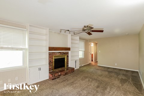A living room with a fireplace and a fan.