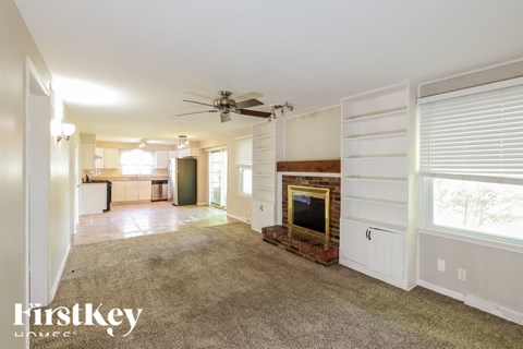 A spacious living room with a fireplace and a ceiling fan.