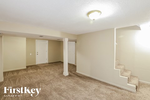 A spacious room with a staircase and a carpeted floor.