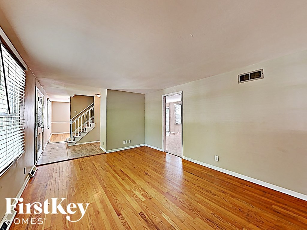 A room with wooden floors and a staircase leading to another room.