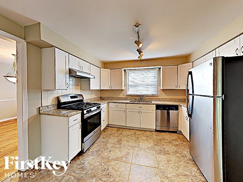 A kitchen with a black fridge and a stove top oven.