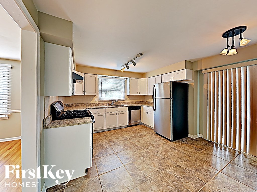 A kitchen with tile flooring and a refrigerator.