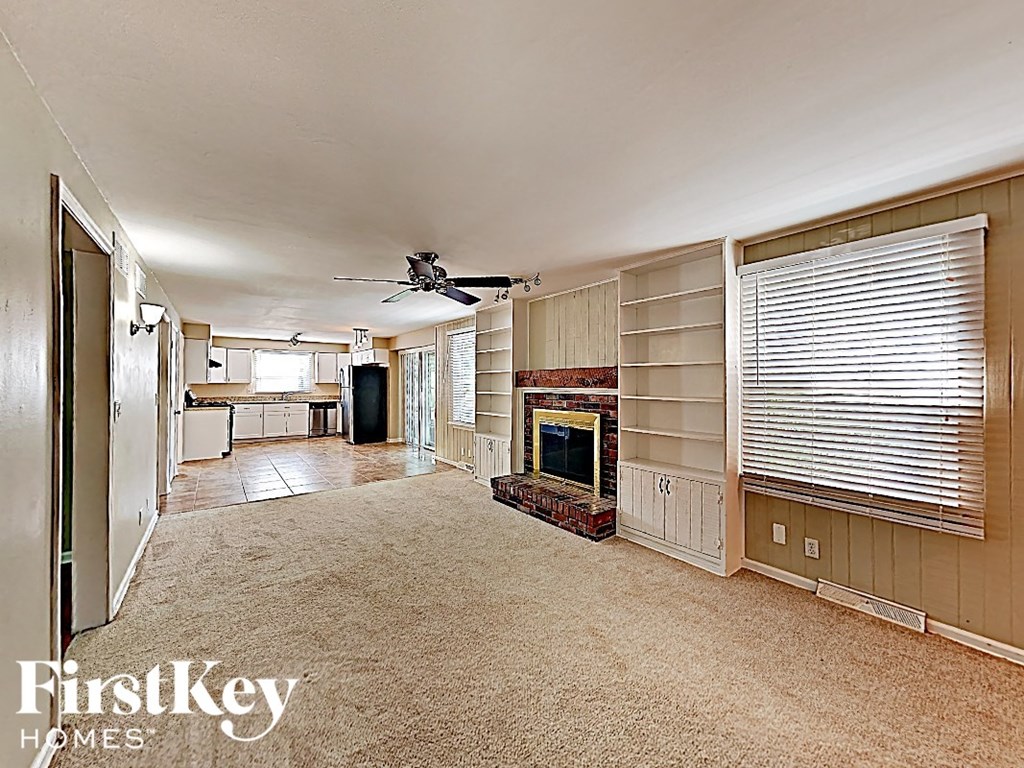 A spacious living room with a fireplace and a ceiling fan.