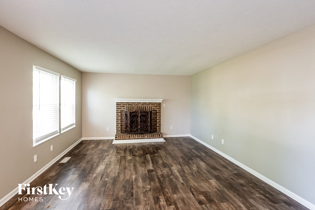 an empty living room with a fireplace and wooden floors