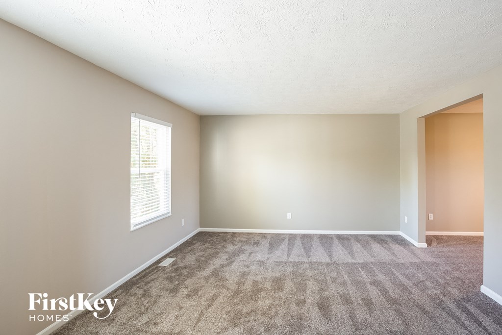 an empty living room with carpet and a window
