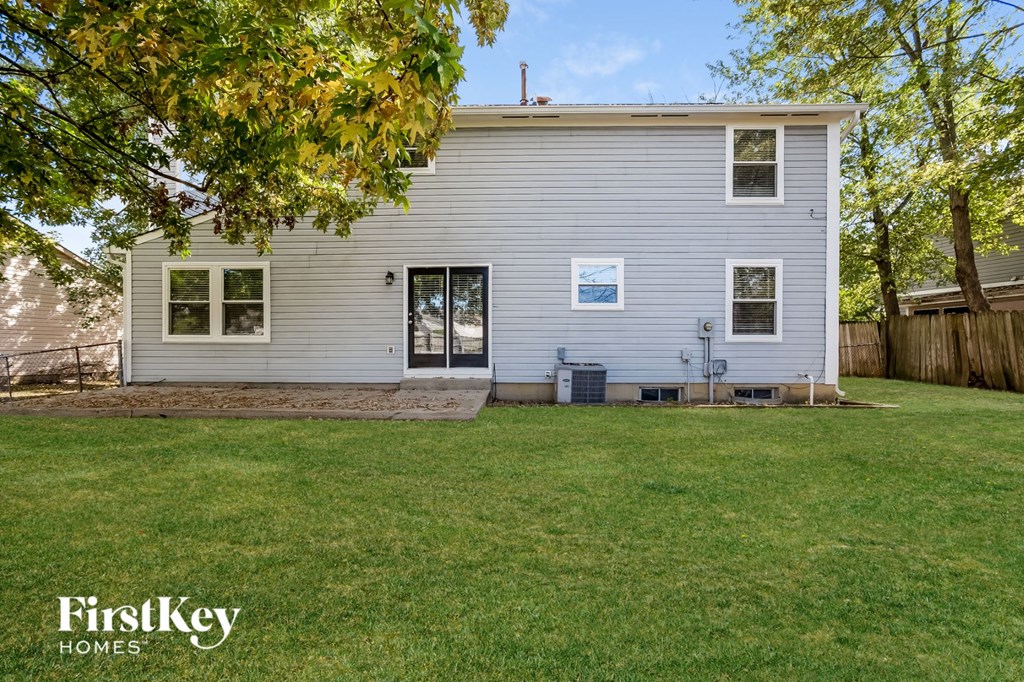 the back of a white house with a lawn and a backyard