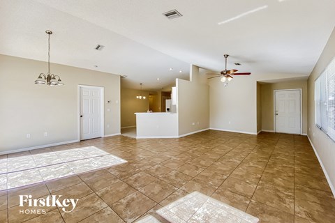 A spacious room with a fan and a rug on the floor.