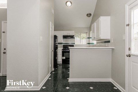 A kitchen with black tile flooring and white walls.