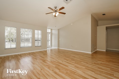 A spacious room with wooden floors and a ceiling fan.