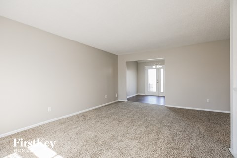 a spacious living room with carpet and a door to the dining room