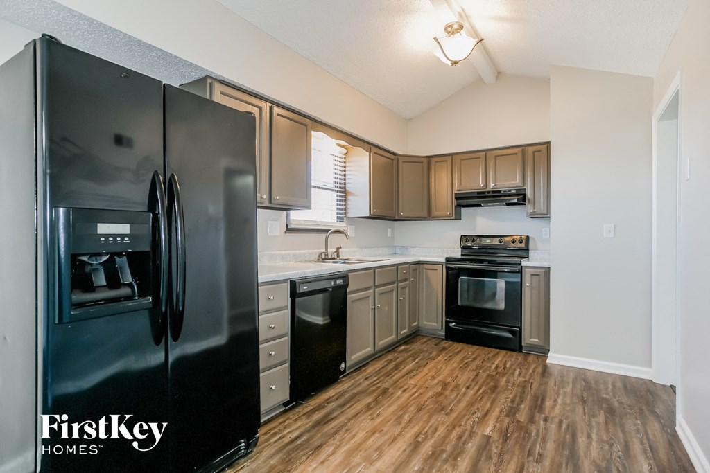 a kitchen with black appliances and wood flooring