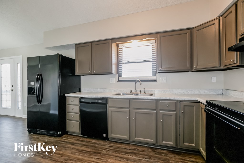 a kitchen with black appliances and white counter tops and gray cabinets
