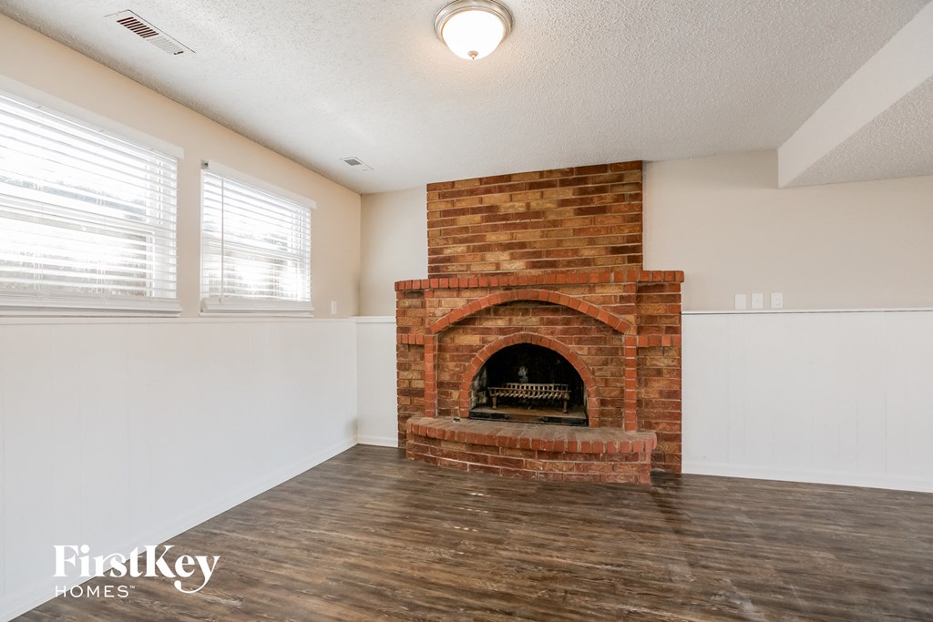 a living room with a brick fireplace and a wooden floor