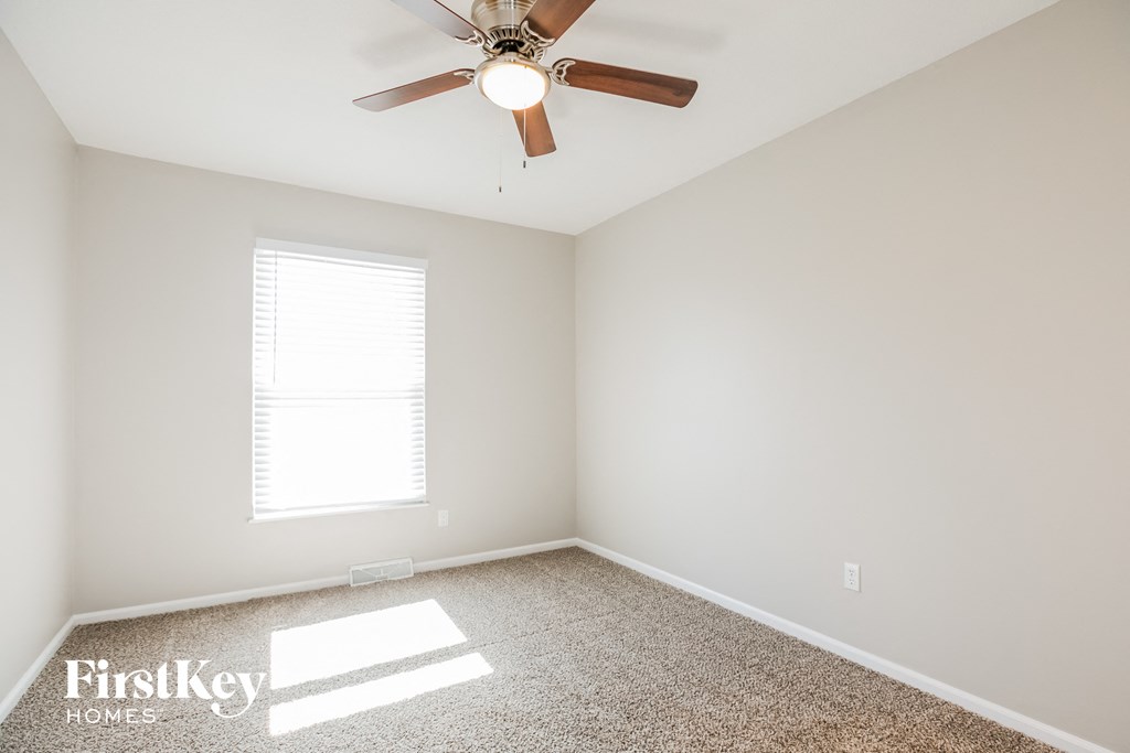 an empty room with a ceiling fan and a window