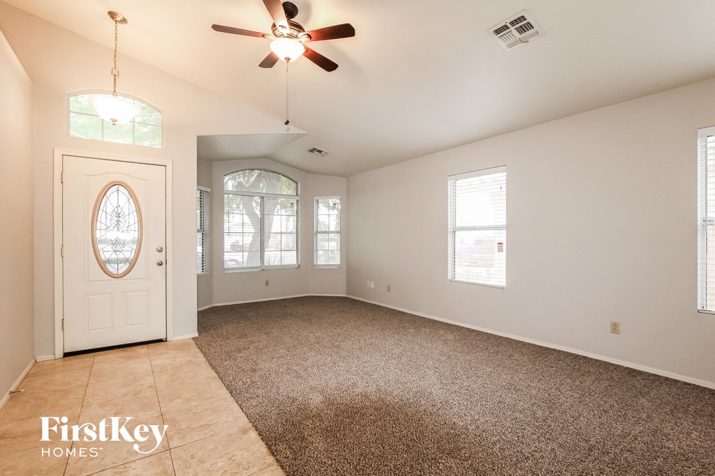 A spacious room with a carpeted floor and a ceiling fan.