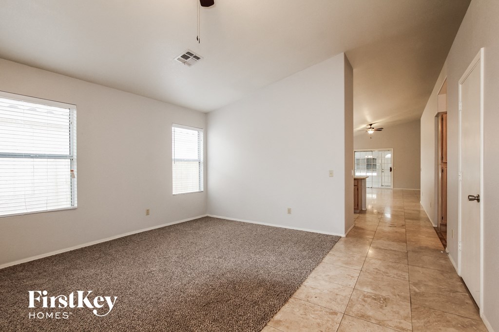 A spacious room with a carpeted floor and a tiled floor leading to another room.