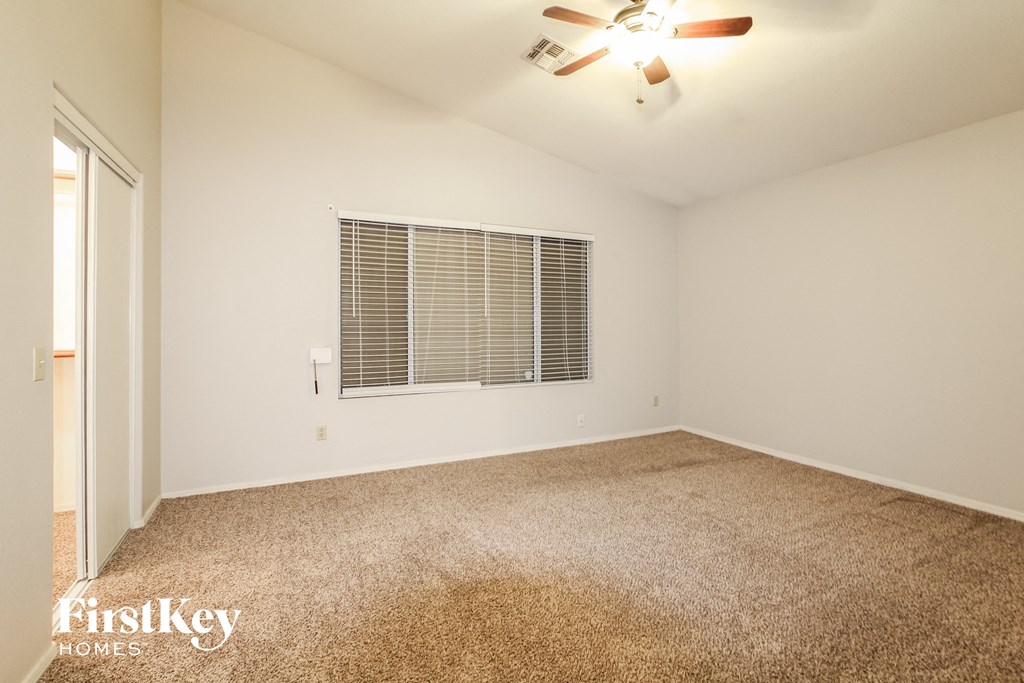 A room with a carpeted floor and a ceiling fan.
