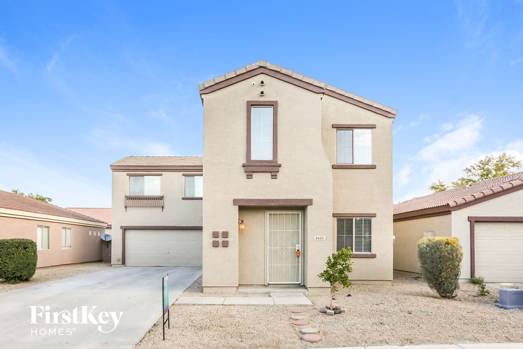 a beige house with two garage doors and a driveway