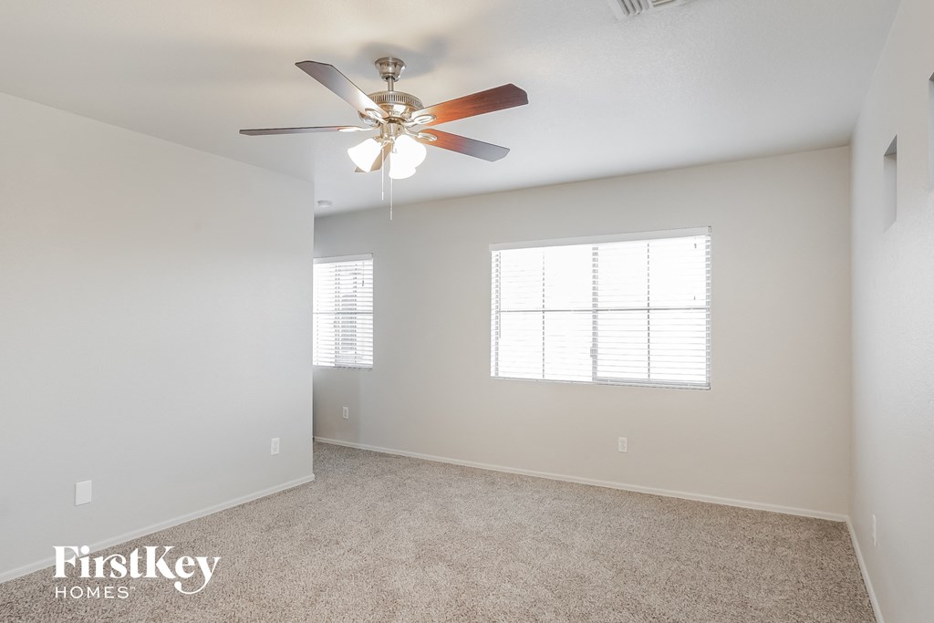 the spacious living room with ceiling fan and carpeting