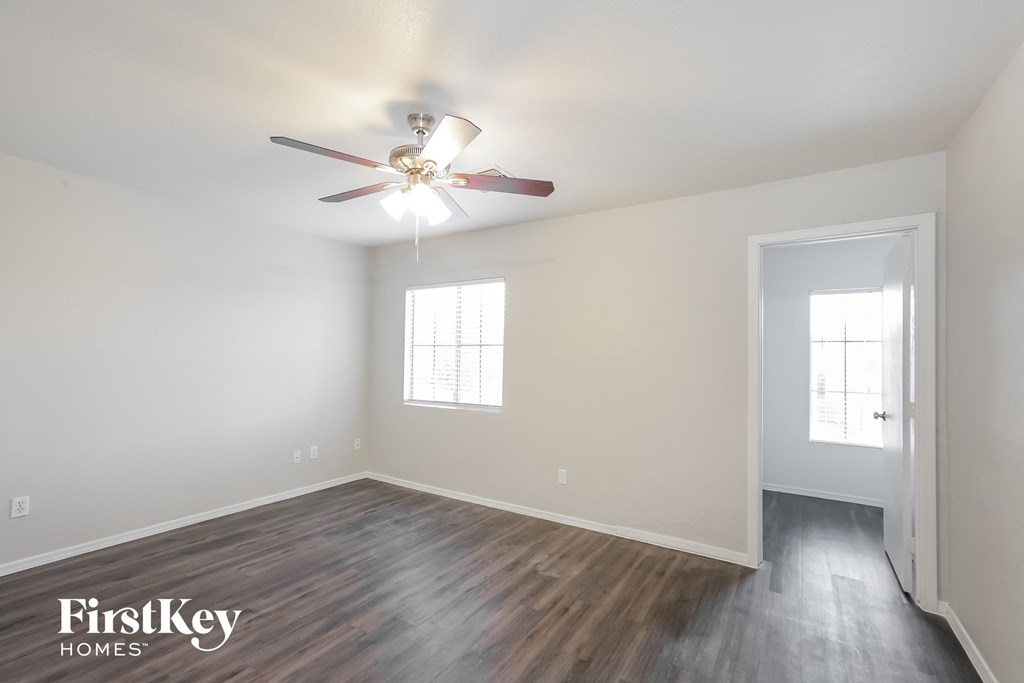 the spacious living room with wood flooring and a ceiling fan