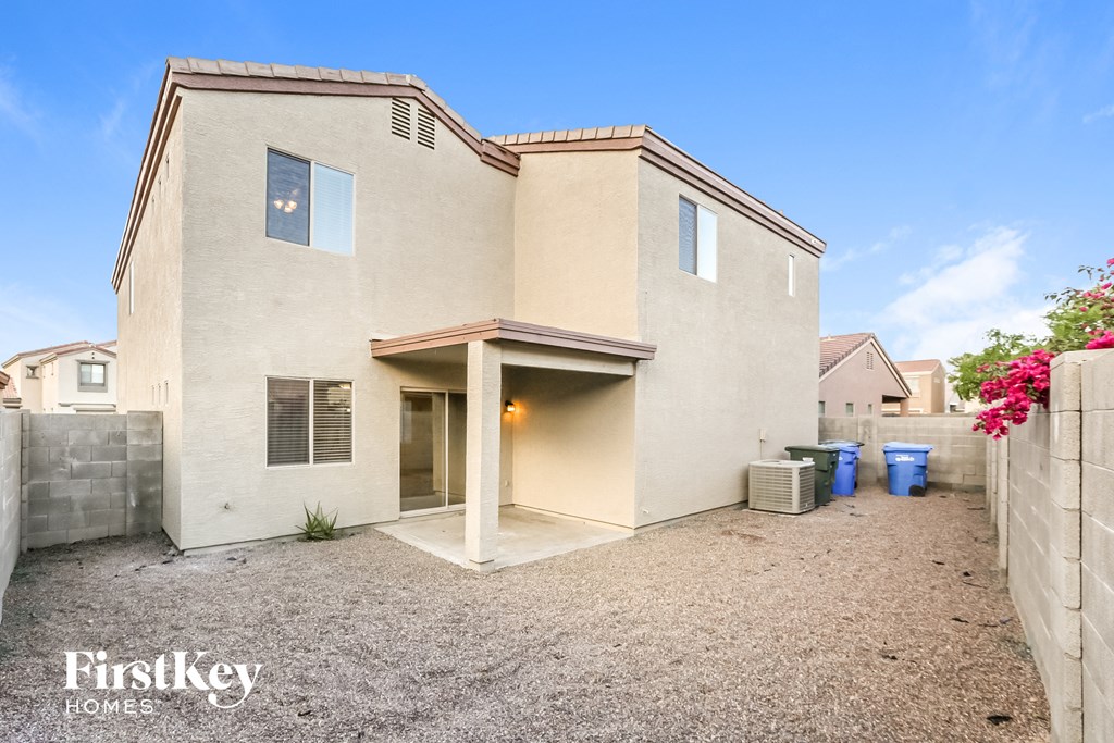 a beige house with a gravel yard and a driveway
