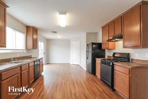 an empty kitchen with wood flooring and black appliances
