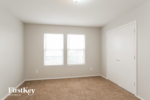 a bedroom with two windows and a door