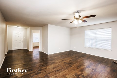 an empty living room with wood flooring and a ceiling fan