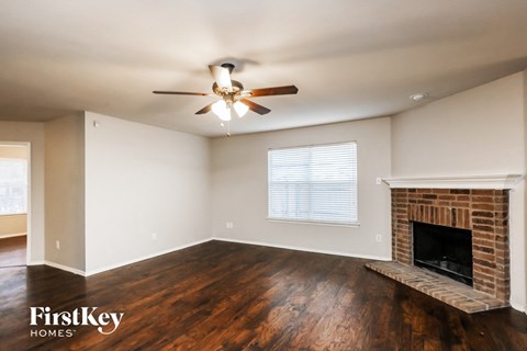 a living room with a brick fireplace and a ceiling fan