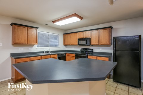 a kitchen with black countertops and wooden cabinets and a black refrigerator