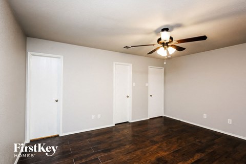 a bedroom with white walls and a ceiling fan and wood floors