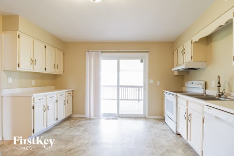 a kitchen with white cabinets and a door to a balcony
