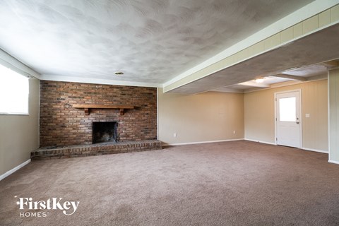 a living room with a brick fireplace and a carpeted floor