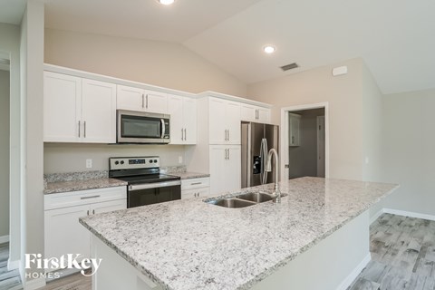 a kitchen with white cabinets and a marble counter top