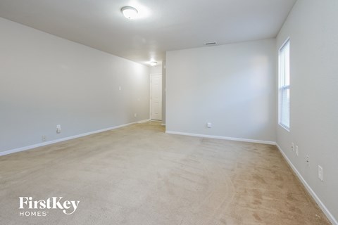 the living room and dining room of an apartment with white walls and flooring