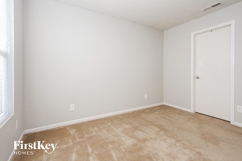 a bedroom with white walls and a white door and a carpeted floor