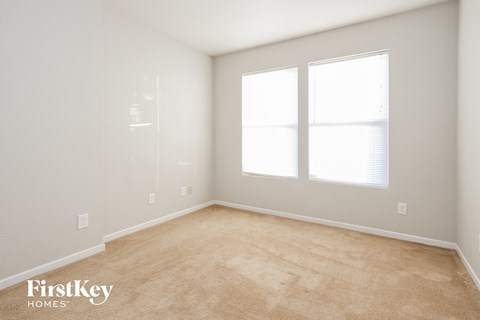 a bedroom with a carpeted floor and two windows