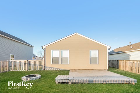 a backyard with a wooden house with a deck and a fire pit