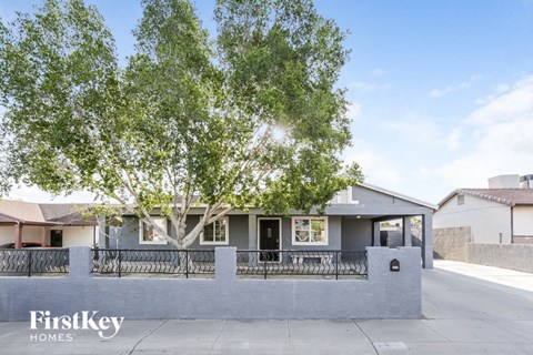 A house with a tree in front and a fence around it.