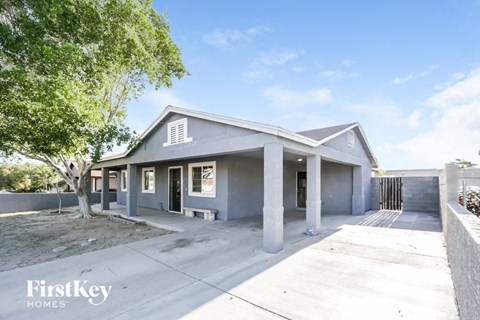 A house with a grey roof and a tree in front of it.