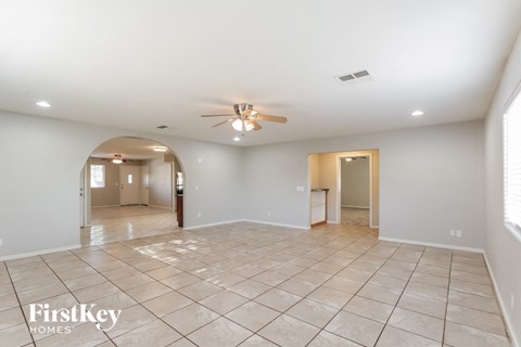 A spacious empty room with a fan on the ceiling.