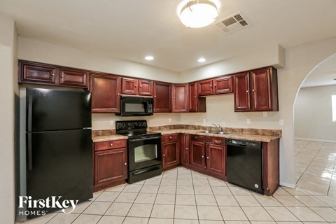 A kitchen with brown cabinets and black appliances.