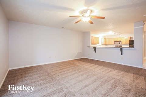 a spacious living room with carpet and a ceiling fan