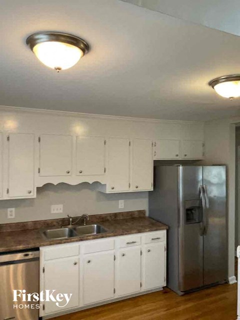 A kitchen with white cabinets and a stainless steel refrigerator.