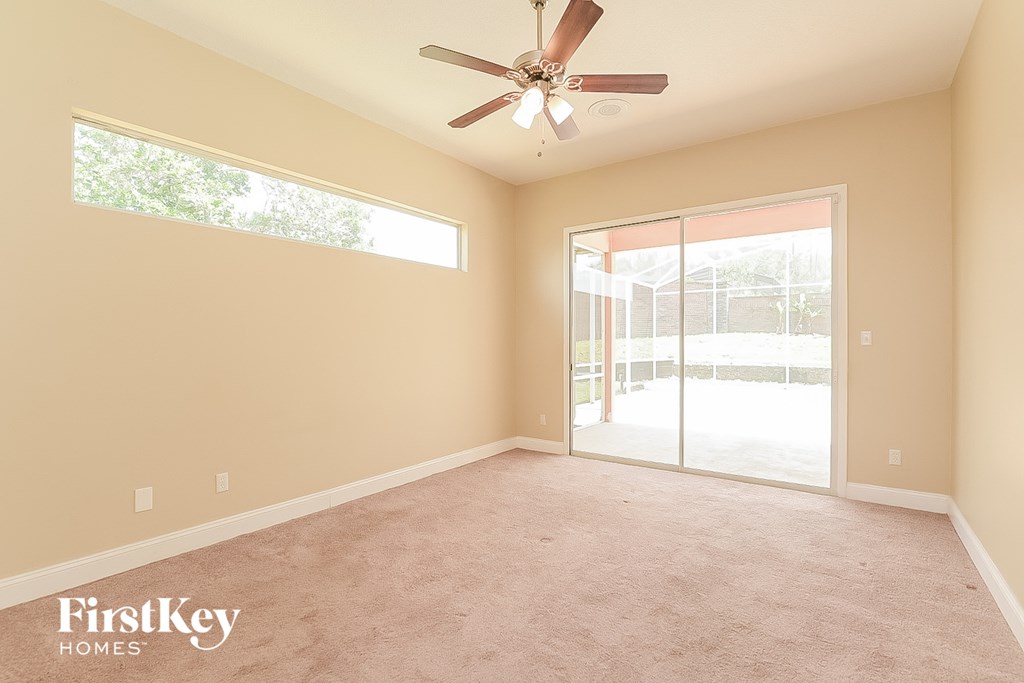 an empty living room with a ceiling fan and a sliding glass door