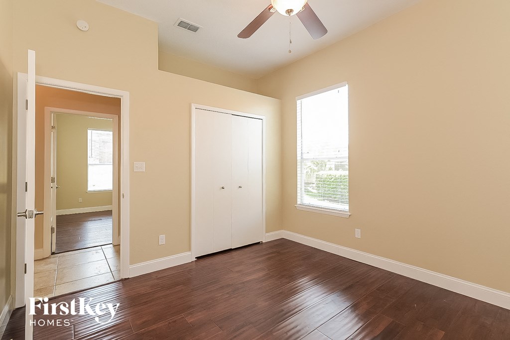 an empty living room with wood floors and a ceiling fan