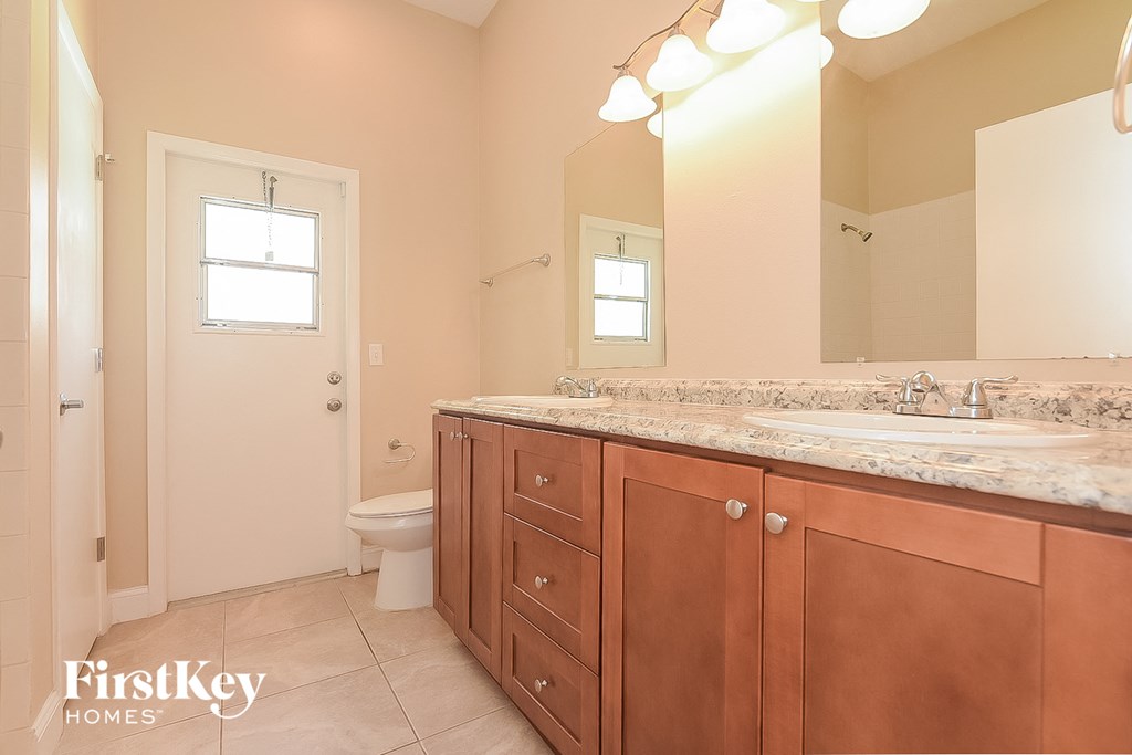 a bathroom with wooden cabinets and a toilet and a sink