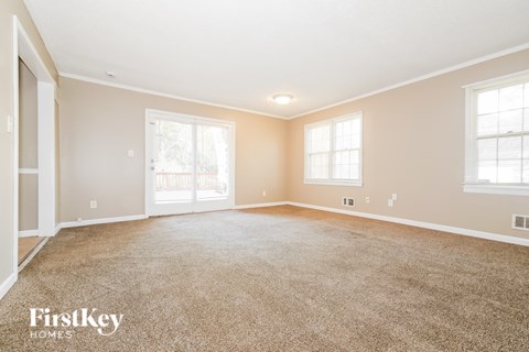 A spacious room with a carpeted floor and a sliding glass door.