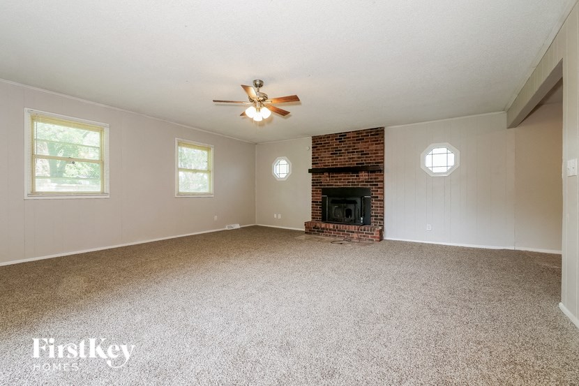 an empty living room with a fireplace and a ceiling fan